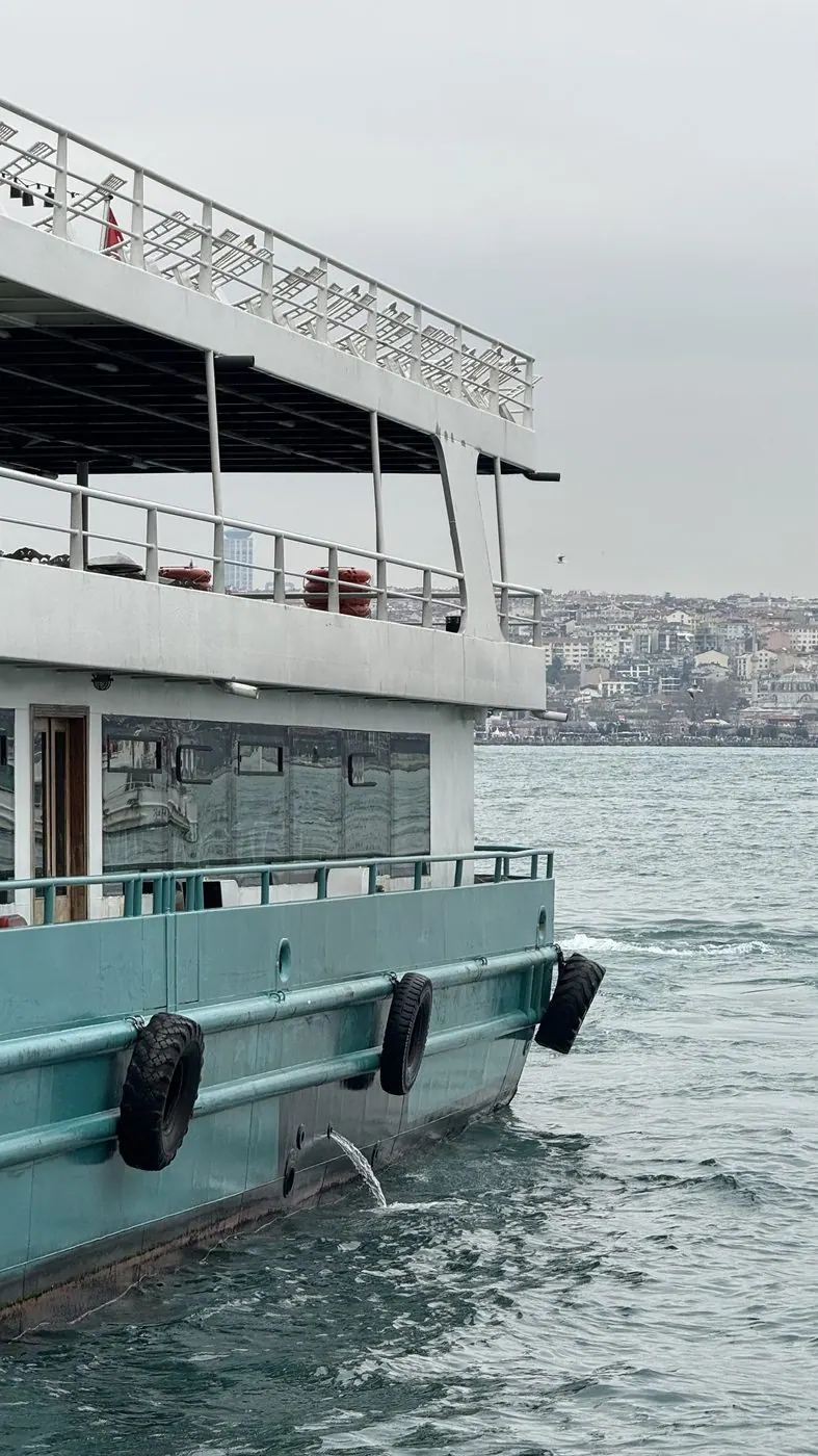 A ferry on open water with a city skyline behind it